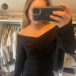 Svart omlott offshoulder topp - Säljer en svart långärmad topp med omlott-design och är offshoulder. Endast använd ett fåtal gånger.