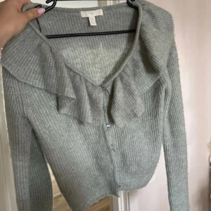 Grå kofta med volang från H&M - Säljer denna snygga kofta🥰 vill bara bli av med blusen!!