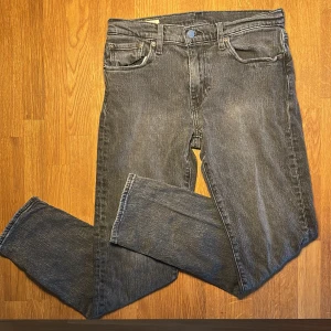Levi's 502 mörkgrå jeans W30 L32 - Levi's 502 jeans i mörkgrå wash med klassisk ficksdesign och raka ben. Jeansen har metallknappar och dragkedja. Perfekta för dig som gillar en clean och lite ”street” look. Lite slitage på framfickorna, syns på bilden. Säjer på grund av för liten storlek🙃