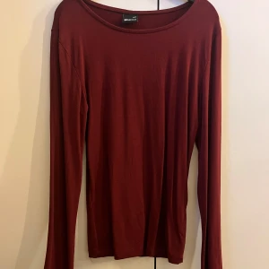 Vinröd långärmad tajt tröja Gina Tricot - Snygg vinröd långärmad tröja från Gina Tricot i storlek XXS. Tröjan har en enkel och stilren design med rund hals och figurnära passform. Perfekt att matcha med jeans eller kjol för en clean look. Materialet känns mjukt och skönt mot huden. Super snygg och perfekt för både vardag men passar även för en festligare look! Använd ett fåtal gånger men inga tecken på användning (för utom att det kan sticka ut trådar på något ställe) men det förstör inte utseendet❤️❤️