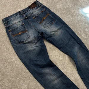 Nudie Jeans - Tjena! Säljer dessa schyssta blå Nudie jeans med fet tvätt och najs slittningar! Jeansen är utav modellen ”Avarage Joe” och har en straight passform. Size 32/34. Bra skick, har en väldigt svag liten fläck på ena benet (bild 5) men syns inte vid använding. Skriv vid funderingar!