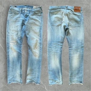 Ljusblå slitna jeans från Evisu - Snygga evisu jeans. Midjemått: 41 cm, ytterbenslängd: 101 cm, fotvidd: 19 cm. 