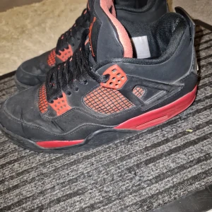 Svarta och röda Nike Air Jordans - Säljer ett par svarta och röda Nike Air Jordans med klassisk Jumpman-logga på hälen. Skorna har svarta snören, meshdetaljer och röda accenter på sula och snörning. Perfekta för dig som gillar streetwear och sneakers med attityd.