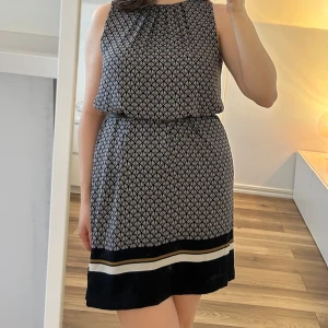 Mönstrad klänning från H&M - Säljer en klänning från H&M i storlek M. Klänningen är ärmlös och har en rak passform. Den har ett geometriskt mönster med en dekorativ kant nertill i mörkblått, beige och vitt. 