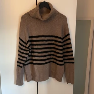 Beige och svart randig stickad polotröja från 157 - Mysig stickad polotröja i beige med svarta horisontella ränder från lager 157!