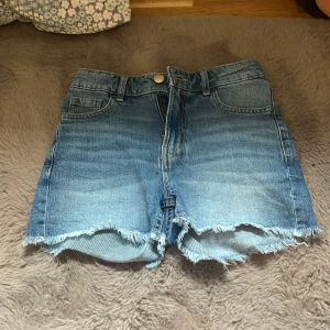 Blåa jeansshorts - Ett par blåa jeansshorts från Lindex i storlek 140. Mid-rise och perfekta till alla sorters tröjor!