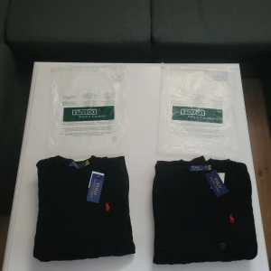 Svart tröja från Polo Ralph Lauren - Säljer 2 helt nya svarta tröjor från Polo Ralph Lauren med klassisk röd broderad logga på bröstet. Tröjorna har en rund halsringning och långa ärmar. Perfekt för en stilren och enkel look. En tröja är i storlek S och en är i storlek M