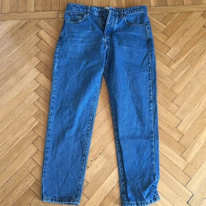 Blå tapered jeans från Ami - Säljer ett par klassiska blå jeans från Ami med tapered fit. Jeansen har fem fickor, normal passform upptill och smalnar av nedtill. Perfekta för dig som gillar stilrena och tidlösa jeans med snygg tvätt.