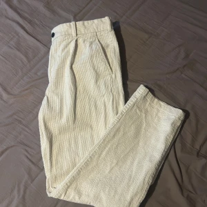 Beige vita manchesterbyxor från H&M - Snygga beige vita manchesterbyxor från H&M i regular fit. Klassisk passform med knapp och dragkedja i midjan samt sidfickor. Perfekta för en stilren och avslappnad look.
