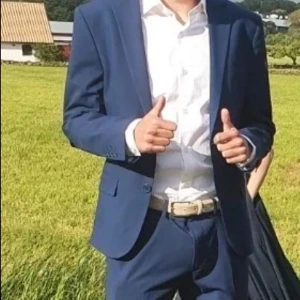 Blå kostym från Dressmann - Säljer en stilren blå kostym från Dressmann i storlek 46S (slim fit). Kostymen består av en kavaj med två knappar och klassiska fickor samt matchande kostymbyxor. Perfekt för bal eller student. Materialet känns lätt och passar bra till vår och sommar.