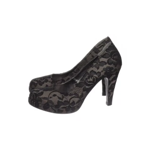TAMARIS Svarta pumps med spets och blommönster St 38 - Säljer ett par eleganta svarta pumps med hög klack och rund tå. Skorna är täckta av svart spets med blommigt mönster och har en plattform framtill för extra komfort. Perfekta för dig som vill sticka ut med en stilren och feminin look.