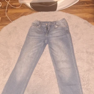 Blå jeans från ZARA - Säljer ett par klassiska blå jeans från ZARA med normal passform och raka ben. Jeansen har fem fickor, dragkedja och knapp framtill. Perfekta till vardags och lätta att matcha med olika stilar.