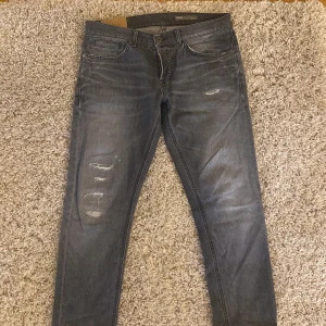Grå jeans från Dondup - Säljer ett par grå skinny jeans från Dondup i modellen George med slitna detaljer på framsidan. Jeansen är i princip helt nya i stl35