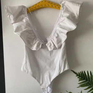 Vit volangbody zara - Elegant vit body med djup v-ringning och volangdetaljer längs axlarna. Från Zara med lappen kvar❤️