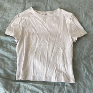  Beige t-shirt från H&M Divided - En klassisk beige t-shirt från H&M Divided. Modellen är enkel med rund halsringning och korta ärmar. Perfekt basplagg i mjuk bomull som passar till allt. Säljes i storlek S. Den är lite kort och slutar lite över naveln.