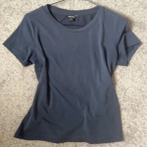 Mörkblå t-shirt från Monki - En basic mörkblå t-shirt från Monki med rund halsringning och korta ärmar. Perfekt att matcha med jeans eller kjol. Tillverkad i mjuk bomull för en skön känsla.