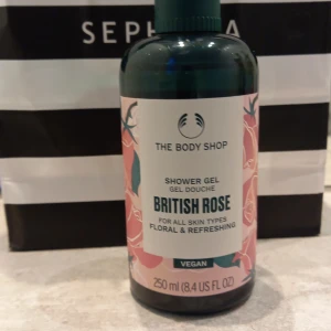 British Rose Shower Gel från The Body Shop - En duschgel med doft av British Rose från The Body Shop. Innehåller 250 ml och är vegansk. Flaskan är grön med rosa blommigt mönster och etikett. Passar alla hudtyper och ger en fräsch, blommig känsla.