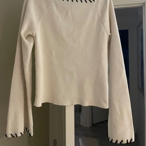 Vit långärmad topp med svarta detaljer - Säljer en vit långärmad topp från Gina Tricot med svarta dekorativa sömmar längs halsringning och ärmslut. De ä storlek M men sitter som en S. Har används Max 1 gång!