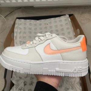 Nya Nike Air Force 1 sneakers - Helt nya, jätte snygga Nike Air Force 1 sneakers i vitt med snygga peach orange detaljer. Säljer för att dom inte är i min storlek. Orginal pris: 1500kr