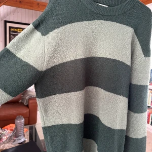 Grön och ljusgrön randig stickad tröja från Zara - Säljer en stickad tröja från Zara i gröna och ljusgröna breda ränder. Tröjan har rund halsringning och långa ärmar. Perfekt för dig som gillar en avslappnad och mysig stil. Storlek M