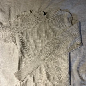Vit stickad tröja från H&M Divided - Säljer en vit stickad tröja från H&M Divided i storlek XS. Tröjan har rund halsringning och långa ärmar. Perfekt för lager-på-lager och enkel att matcha med olika outfits.