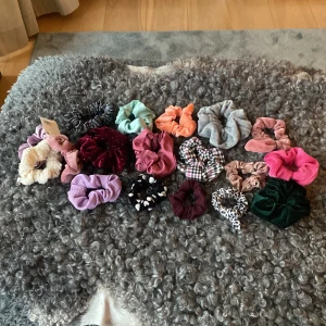 Färgglada scrunchies i olika material och mönster - Säljer ett set med scrunchies i flera färger och material, inklusive sammet, fuskpäls och bomull. Färgerna varierar från rosa, lila, grön, svart, vit till mönstrade varianter som rutig och leopard. Perfekt accessoar för håret!