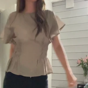 Söt topp från H&M💕 - Säljer en grön blus med rund halsringning och korta, vida ärmar. Blusen har smockdetaljer i midjan. Det är filter på dem två andra bilderna men de är samma tröja. 