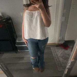 Vit linnetopp från H&M - Säljer en enkel och luftig vit linnetopp från H&M. Toppen har tunna axelband och rak passform, perfekt för varma dagar. Materialet är lätt och har en lite skrynklig struktur. Snygg att matcha med jeans eller kjol!