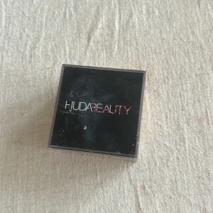 Huda Beauty Setting Powder Blondie -Öppnad men inte använd! - Lös puder från Huda Beauty i nyansen Blondie. Perfekt för att sätta sminket och ge en matt finish. Kommer i en fyrkantig transparent burk med svart lock. Pudret är ljusgult och passar för baking och fixering av makeup. - säljer pga färgen är för orange för mig och har ingen vän som är behov av det.