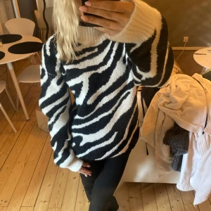 Zebramönstrad stickad tröja - Säljer en mysig stickad tröja med zebramönster i svart och vitt. Tröjan har lång ärm och en klassisk rund halsringning. Perfekt för dig som vill sticka ut lite extra i vardagen.