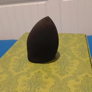 Svart beautyblender - En svart beautyblender i mjukt skumgummimaterial, perfekt för att applicera foundation eller concealer jämnt över ansiktet. Den har en droppformad design som gör det enkelt att komma åt både större och mindre partier i ansiktet.