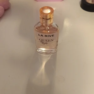 La Rive Queen of Life parfym - Säljer en elegant parfymflaska från La Rive, Queen of Life. Flaskan är genomskinlig med guldigt lock och svart text. Perfekt för dig som gillar fräscha och feminina dofter.