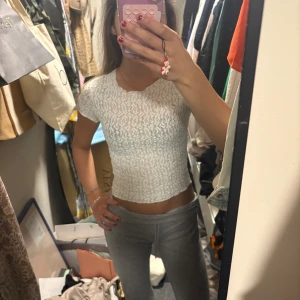 Vit croppad topp  - Säljer en vit croppad topp med korta ärmar och ett krusigt, ribbat mönster. Toppen har en tight passform och är perfekt att styla med jeans eller kjol. Skriv för fler bilder eller info🥰