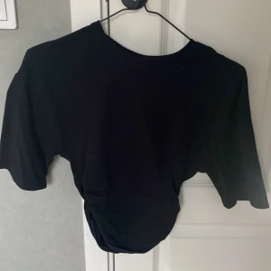 Svart topp från Gina Tricot - En svart topp från Gina Tricot i storlek XXS. Toppen har korta ärmar och en enkel, stilren design. Perfekt att matcha med både jeans och kjol för en trendig look.