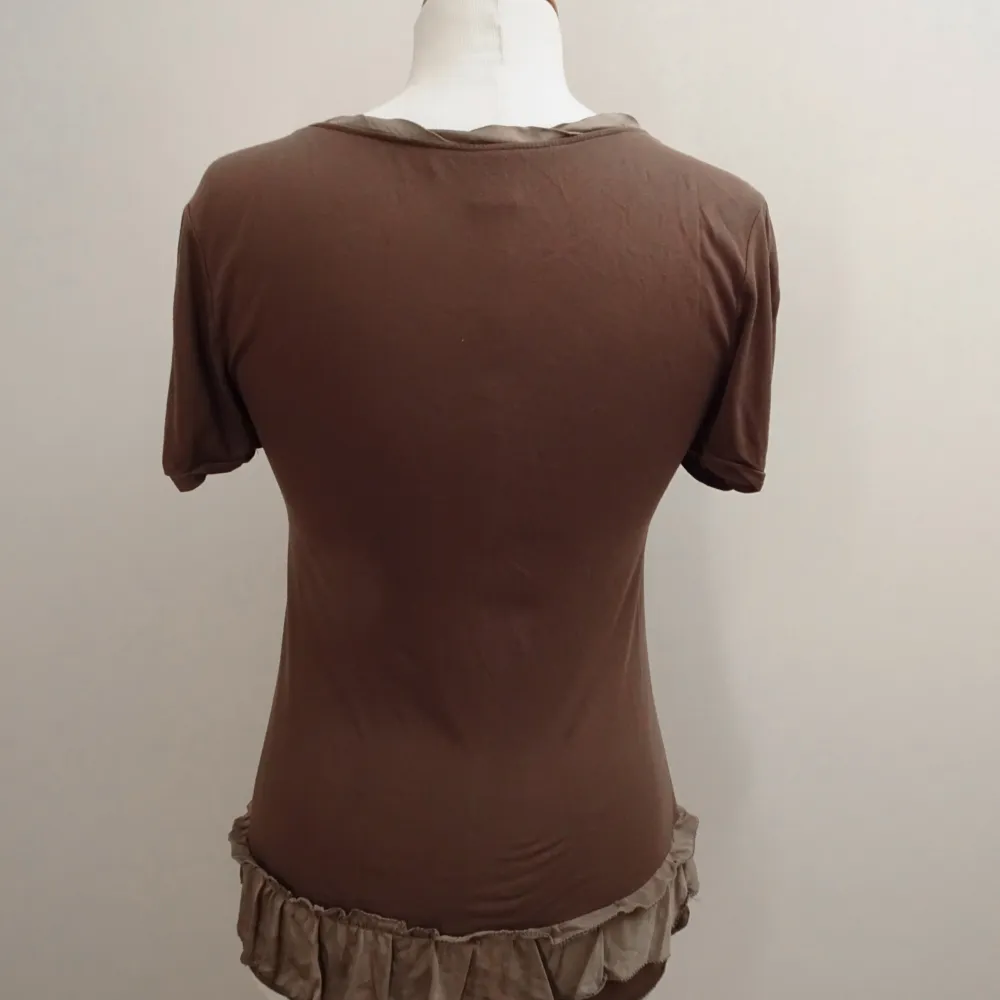 Marc by Marc Jacobs grön/ khakifärgad topp med korta puffärmar och dekorativa detaljer. Den har en rund halsringning med en smal kant och en knappslå med små knappar. Nedtill finns en volang. Använd men i bra skick Axlar: 40cm Byst: 39cm Längd: 61cm. T-paidat.