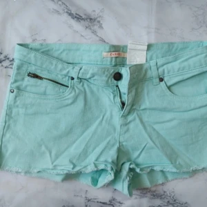 Turkosa lågmidjade jeansshorts - Snygga mintgröna jeansshorts från Camaïeu med råa kanter och klassisk femficksdesign. Shortsen har dragkedja och knapp framtill samt en liten extra ficka med dragkedja. Perfekta för varma dagar! Skriv till mig innan du köper!💕
