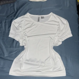 Vit t-shirt/ magtröja från H&M Divided  - En basic vit t-shirt från H&M Divided.  Tillverkad i ett mjukt och stretchigt material som känns skönt mot huden. Säljer den pga att man kan se igen ganska mycket . Ord. 49kr. 