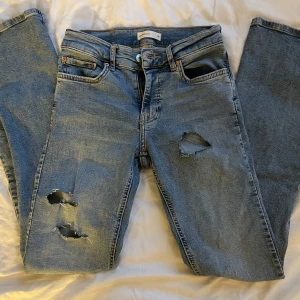Ljusblå jeans med hål - Säljer ett par ljusblå jeans från Gina Tricot i modellen Perfect Jeans. Inga tecken på använding, mid-rise och bootcut💕