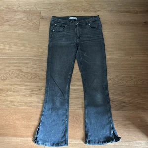 Grå bootcut jeans med slits från zara  - Snygga grå jeans med bootcut passform och slitsar nertill på benen. 