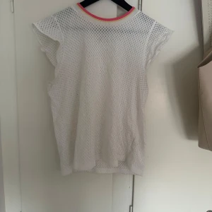 Vit topp🤍 - Säljer en vit topp från & Other Stories med korta volangärmar och rund halsringning med rosa och gul kant. Fint skick och inte använd många gånger! Skriv vid intresse eller funderingar!❤️