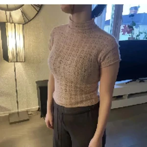 Beige stickad polotopp från Zara - Säljer en beige stickad polotopp från Zara. Toppen har korta ärmar och ett diskret hålmönster i materialet. Perfekt att styla med både jeans och kjol för en trendig look.