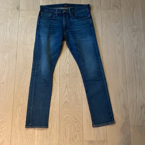Polo Ralph Lauren jeans Sullivan Slim - Snygga blå jeans från Polo Ralph Lauren i modellen Sullivan Slim. Klassisk femficksdesign, normalhög midja och raka ben. Jeansen har en diskret tvätt och är tillverkade i slitstarkt denim. Perfekta för en stilren vardagslook. Strl 32/32!