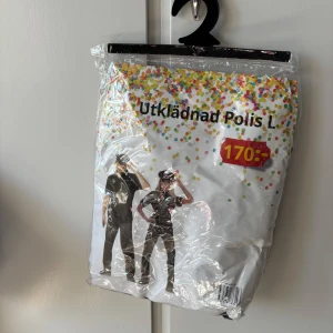 Polis utklädnad L - Säljer en polis utklädnad i storlek L. Dräkten är svart men saknar keps. Perfekt för temafest eller maskerad. Kostymen är förpackad i originalförpackning.