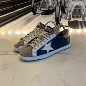 Golden Goose sneakers - Säljer ett par sjukt feta Golden goose i en skön färg som enkelt går att kombinera. De är i ett fint skick med vit sula men lite defekter som syns på bilderna. Hör av er vid minsta fundering🙌