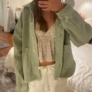 Zara grön jeansjacka - Säljer en ljusgrön jeansjacka med knappar framtill och stora fickor. Jackan har en avslappnad passform och långa ärmar. Perfekt att slänga över en topp för en cool vardagslook.