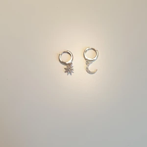 Silverfärgade örhängen med stjärna och måne - Säljer ett par silvriga örhängen som aldrig kommer till användning💓 Det ena är en glittrig stjärna och den andra en glittrig måne⭐🌛
