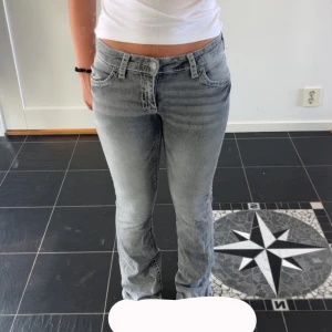 Grå bootcut jeans med broderade fickor - Säljer ett par grå jeans med bootcut-modell och snygga broderade detaljer på bakfickorna. Jeansen har normal passform, klassisk femficksdesign och är tillverkade i mjukt denimtyg. Perfekta för dig som gillar en stilren men ändå unik look.Aldrig använda!!