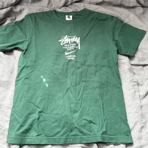 Grön Stüssy x Nike t-shirt - Snygg grön t-shirt från Stüssy och Nike med vit logga och tryck på bröstet. Klassisk passform med rund hals och korta ärmar. Perfekt för dig som gillar streetwear och vill sticka ut med en ikonisk collab. Knappt använd och sällsynt. Skick är som nytt. Passa dig mellan 160-170.