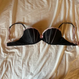 BH ifrån Victoria’s secret - Svart bh med rosa detaljer ifrån Victoria’s secret i strl 36D. I mitten där fram på bh-n finns en rosa rosett. Använd ett fåtal gånger och i mycket bra skick! Hör gärna av er vid frågor eller funderingar, är öppen för förhandling av priset!💕💕