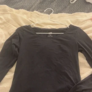 Svart långärmad bomullströja - En basic svart långärmad tröja från lager 157 i mjuk bomull. Tröjan har en rund halsringning och en enkel, stilren design som funkar till allt. Perfekt att matcha med jeans eller kjol för en clean look.